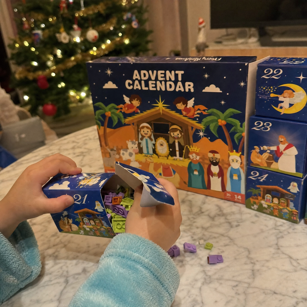 Child opening a numbered daily box from the Holy Advent Calendar